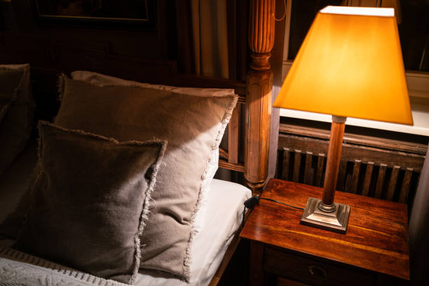 istock Lamp on a night table next to a bed 1182902624