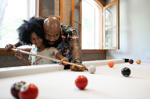 Father is teaching daughter how to play snooker