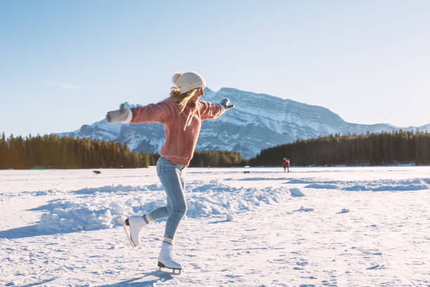 jeune femme patinant sur le lac gelé au coucher du soleil ayant l'amusement et appréciant des vacances d'hiver - snowshoeing snowshoe women shoe photos et images de collection