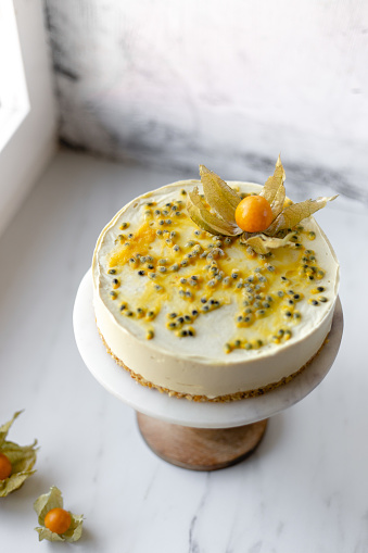 Passionfruit vegan cheesecake with Physalis on marble background with copy space