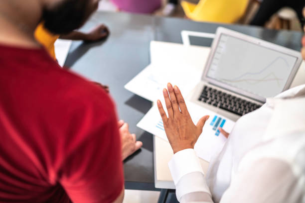 istock Mid section of finance advisor showing data to clients, using laptop and papers with diagrams and graphs 1182904910