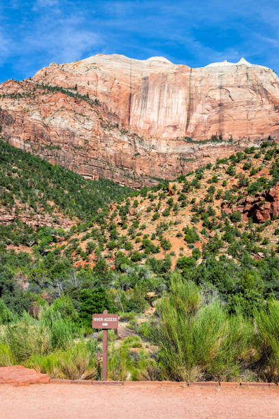 Vertical view red orange Zion National Park cliffs desert landscape during summer day with tall high rock formations and sign for river access Vertical view red orange Zion National Park cliffs desert landscape during summer day with tall high rock formations and sign for river access virgin river stock pictures, royalty-free photos & images