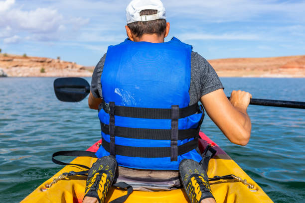 солнечный день на озере пауэлл с тандемом каяк и ноги с задней человек каяках в лодке и вид на каньоны воды, весло и спасательный жилет - women kayaking life jacket kayak стоковые фото и изображения