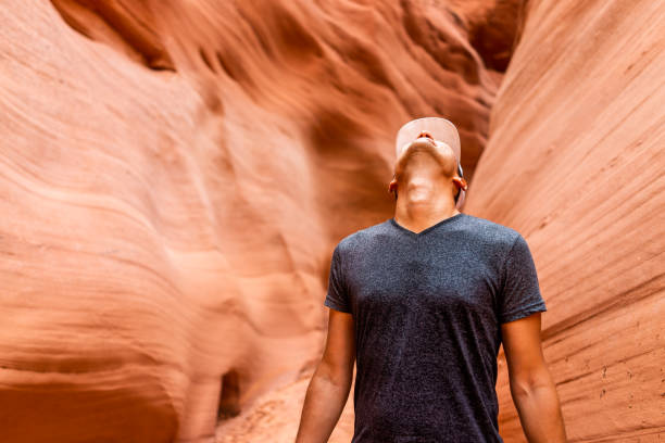 Man looking up at red wave shape formations at Antelope slot canyon in Arizona on footpath trail from Lake Powell Man looking up at red wave shape formations at Antelope slot canyon in Arizona on footpath trail from Lake Powell lower antelope canyon stock pictures, royalty-free photos & images