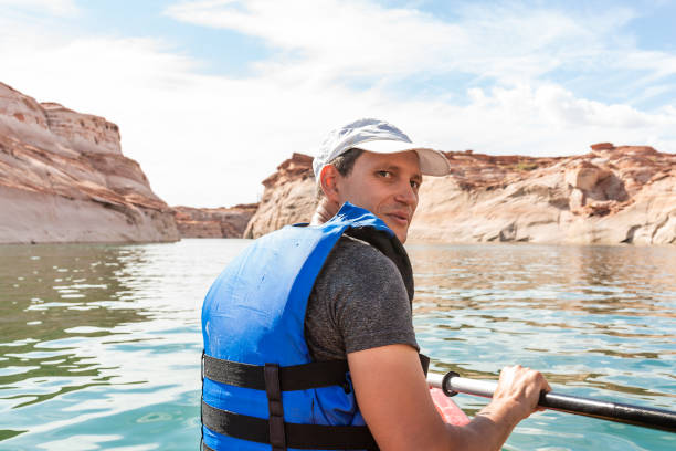 mann kajakfahren in lake powell wasser antilopen schlucht blick zurück mit paddel ruder und schwimmweste weste - water reflection marina life jacket stock-fotos und bilder