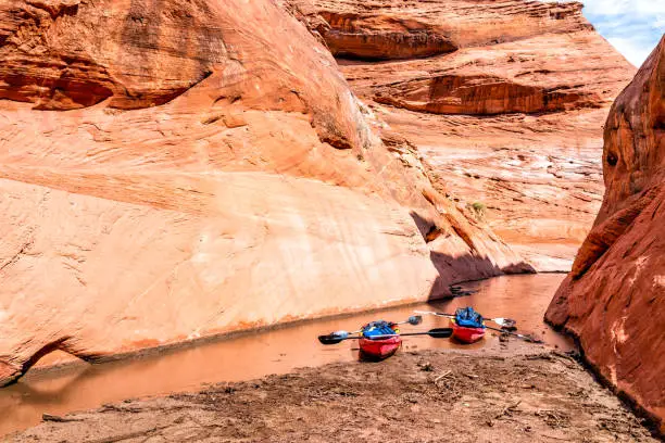 Photo of Kayaks by trailhead of hiking trail in Lake Powell narrow and shallow antelope canyon with dirty muddy water and rock formations