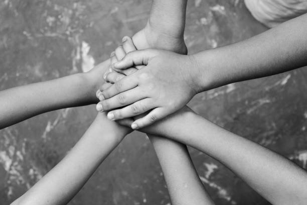 istock children hand together in a circle with palms down on gray background.black and white. 1182909828