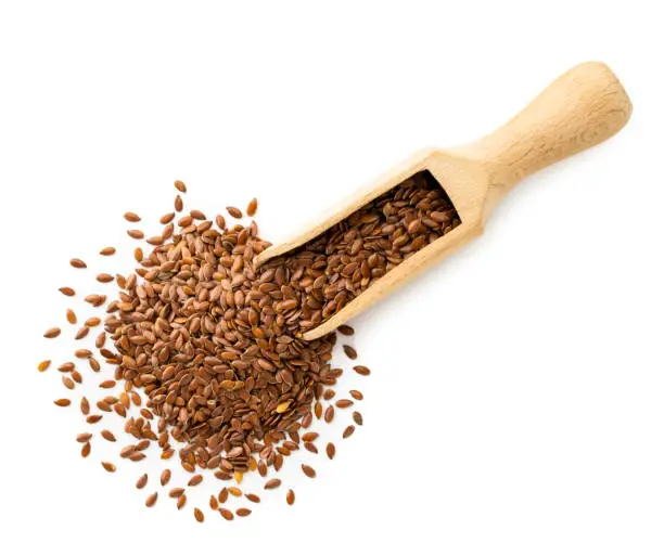 Flax seeds in a wooden scoop on a white background, isolated. The view of the top.