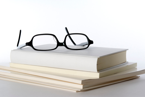 Stacked blank white books with black frame glasses isolated on white background.