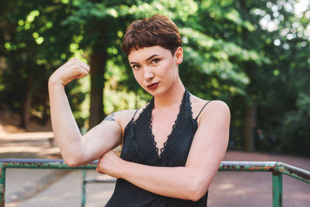 Cropped portrait of an attractive young woman flexing her bicep while standing in a park during the day