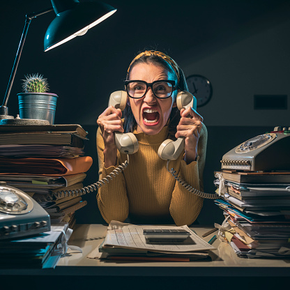 Angry stressed secretary working overtime and shouting at the customers on the phone