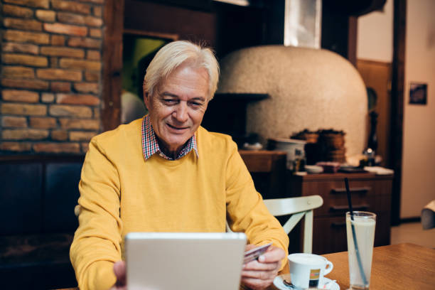 istock Mature man shopping online from the cafe 1182925000