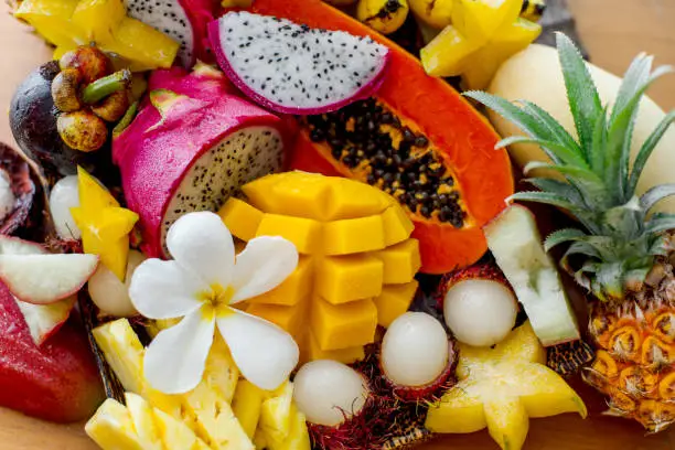 Photo of Juicy ripe tropical Thai fruits on a wooden dish.