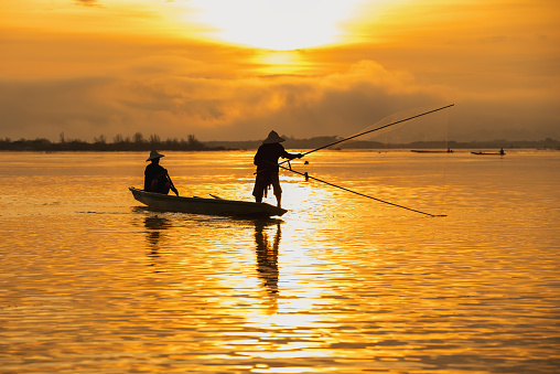 Asian fishermen set sail for fishing on the Mekong River at sunrise.