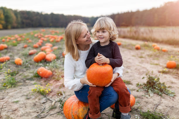 istock Mother and son in pumpkin patch field 1182926787