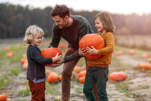 istock Father and sons in pumpkin patch field 1182926789