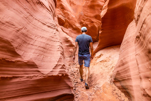 istock Orange red wave shape formations rocks shadows with back of man walking at narrow Antelope slot canyon in Arizona on footpath trail from Lake Powell 1182930003