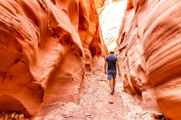 Photo of Man hiker walking by red wave shape formations at Antelope slot canyon in Arizona on footpath trail from Lake Powell