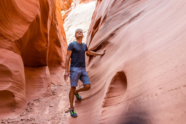 Man hiker looking up touching wall of red wave shape formations at Antelope slot canyon in Arizona on footpath trail from Lake Powell Man hiker looking up touching wall of red wave shape formations at Antelope slot canyon in Arizona on footpath trail from Lake Powell upper antelope canyon stock pictures, royalty-free photos & images