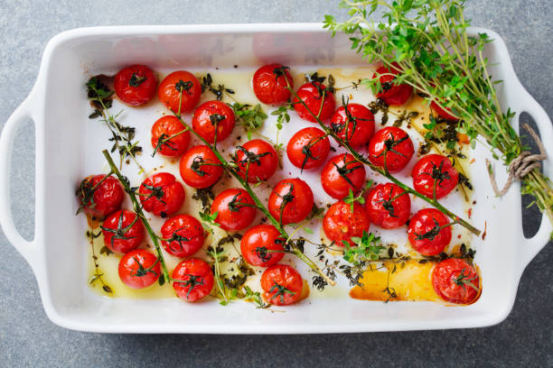 istock Roasted cherry tomatoes with herbs in baking dish. Grey background. Top view. 1182930531