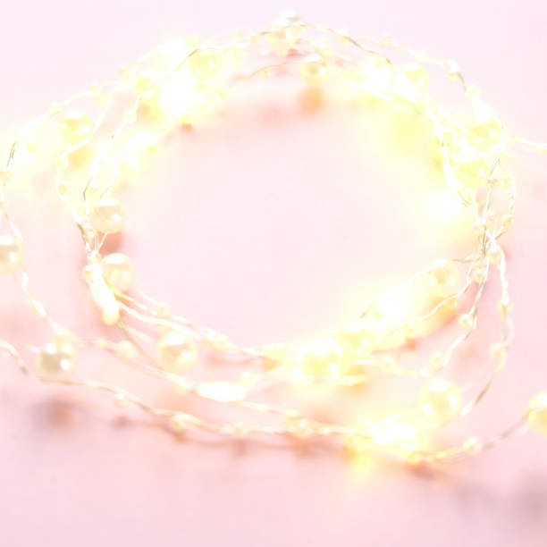 istock Tiny elegant christmas lights border. Round shape made with garland on pink background. 1182931827