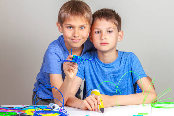zwei kinder beim erstellen mit 3d-druckstiften - light bulb blue energy fuel and power generation stock-fotos und bilder