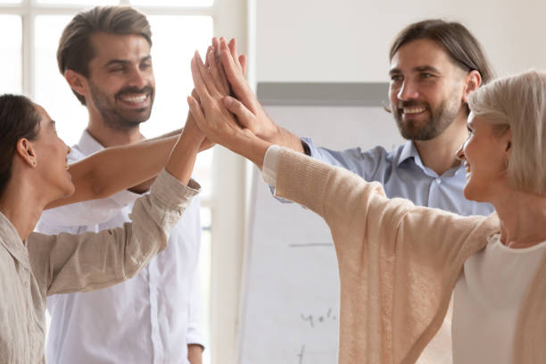 istock Happy company team employees give high five join hands together 1182934108