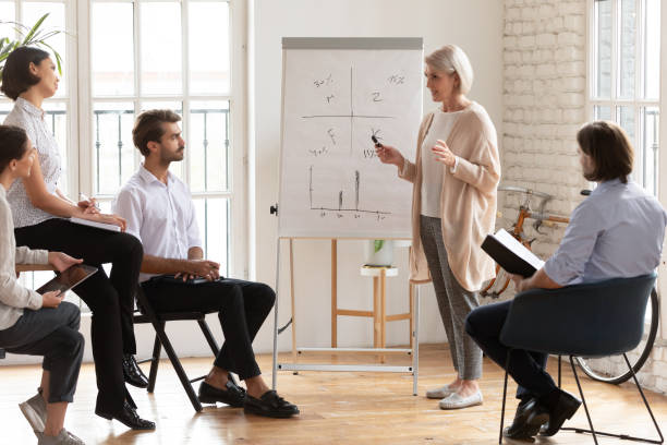 istock Skilled old female mentor give presentation training staff at meeting 1182934361
