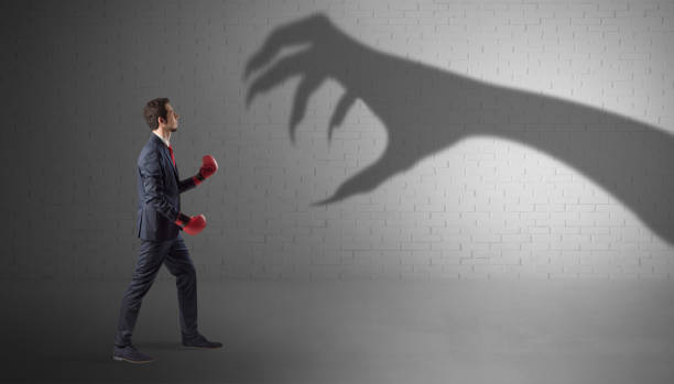 istock Businessman fighting with scary hand shadow 1182939027