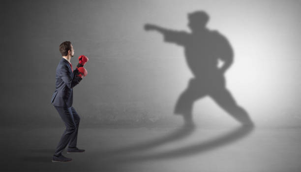 istock Young businessman fighting with his shadow 1182939081