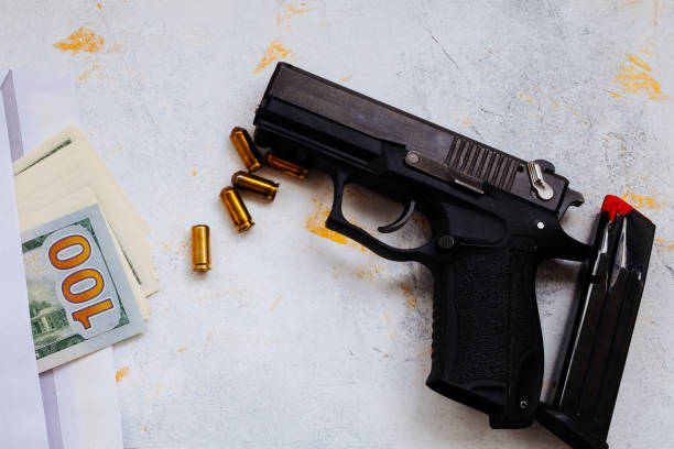 istock 9 mm pistol gun bullets strewn and roll american dollar banknotes on rustic oak table. 1182939704