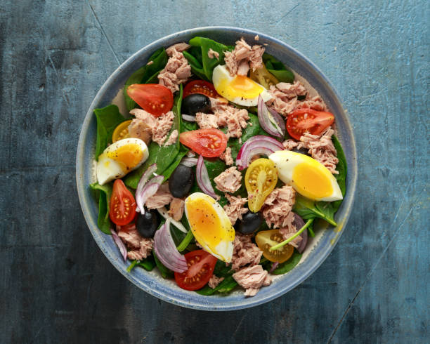 istock Protein packed tuna and soft, runny egg salad with pear shaped cherry tomatoes, black olives and spinach 1182940979
