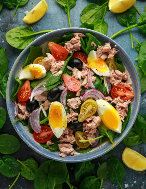 istock Protein packed tuna and soft, runny egg salad with pear shaped cherry tomatoes, black olives and spinach 1182941194