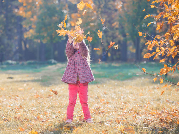 istock Girl, garden, autumn, falling leaves 1182943373