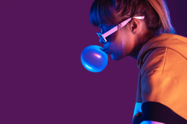 Teen igen girl wear stylish trendy sunglasses and hoodie blowing bubble gum profile side view, pretty young woman fashion cool model with bubblegum 80s at party purple studio background, copy space Teen igen girl wear stylish trendy sunglasses and hoodie blowing bubble gum profile side view, pretty young woman fashion cool model with bubblegum 80s at party purple studio background, copy space bubble gum photos stock pictures, royalty-free photos & images