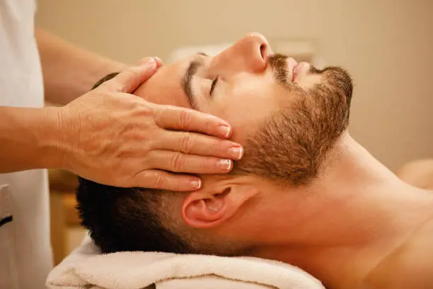 Close-up of man getting head massage and relaxing with eyes closed at the spa.