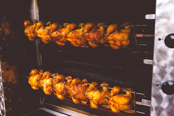 Chicken on the turning spit with tasty golden-yellow roasted skin in 2 rows