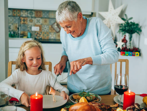 donna anziana che serve tacchino arrosto alla sua adorabile nipote. - turkey carving portion dinner foto e immagini stock