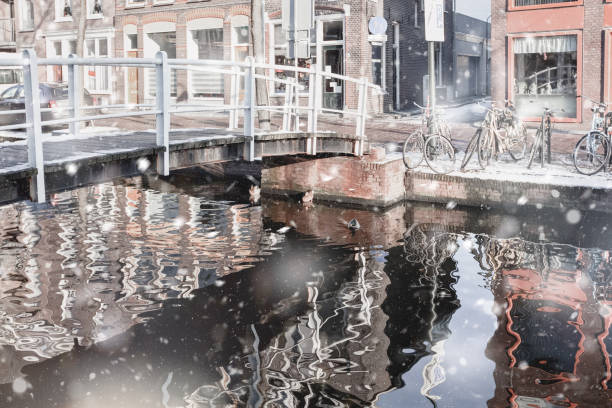House reflection in the canal of Delft House and bridge reflections in the canal of Delft. Pastel trendy toning. Beautiful inspiring moody faded scenery delft winter netherlands snow stock pictures, royalty-free photos & images
