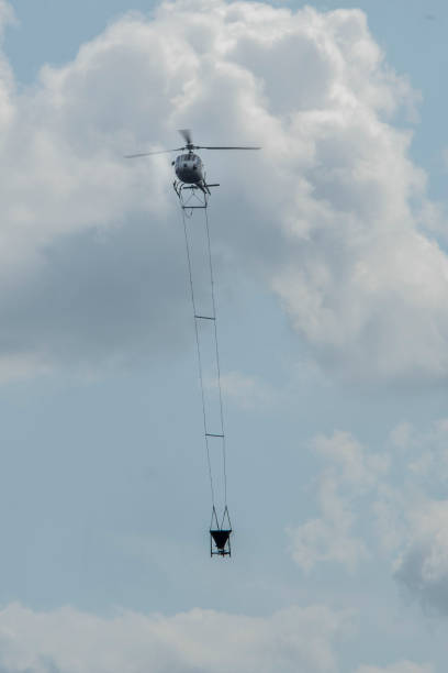 istock helicpter flying with big barrel of lime over a forest 1182950092