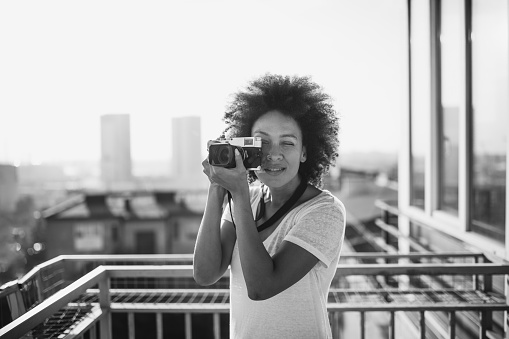 Mixed race woman standing on balcony and taking a photography