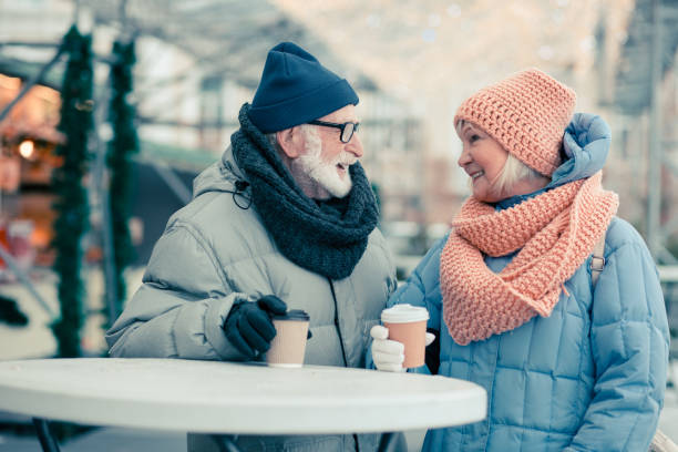 istock Smiling elderly couple drinking coffee at the Christmas fair 1182952823