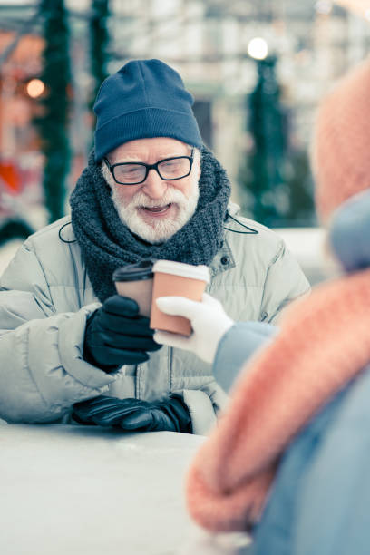 istock Senior man in winter clothes drinking coffee with friend 1182955222