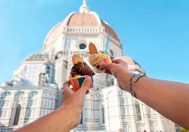 Photo of Women's hands with ice cream Gelato on the background of the city sight Cathedral of Santa Maria del Fiore in the historical center of Florence, Italy, Europe, a famous tourist place