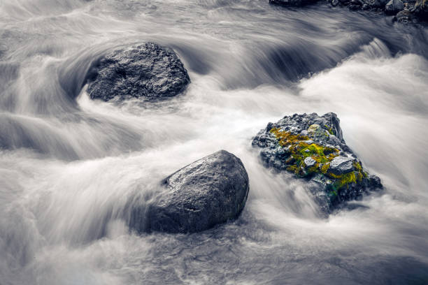 istock Fast water flowing round rocks 1182958897