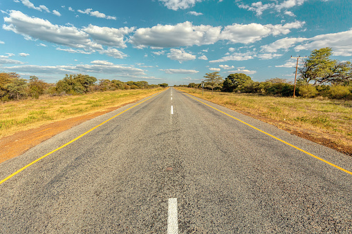 Endless road in Botswana, sunny day with blue sky, Africa