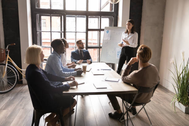 自信のあるビジネスウーマンコーチがビジネストレーニングでホワイトボードプレゼンテーションを行う - conference business meeting training ストックフォトと画像