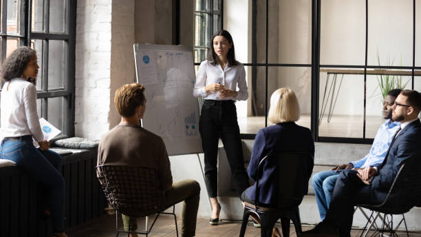 Confident lady business trainer coach give flip chart presentation Confident lady business trainer coach leader give flip chart presentation consulting clients teaching employees training team people speaking explaining strategy at marketing workshop concept benefits photos stock pictures, royalty-free photos & images