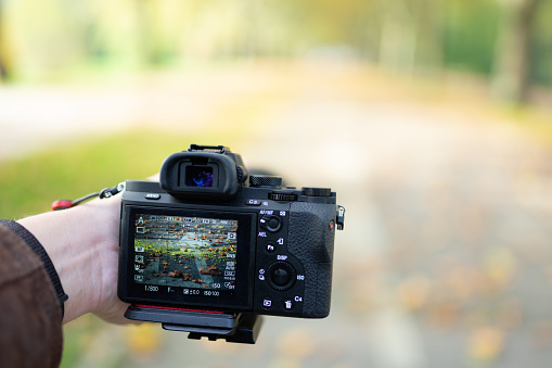 Holding a DSLR camera and taking a picture during fall autumn season