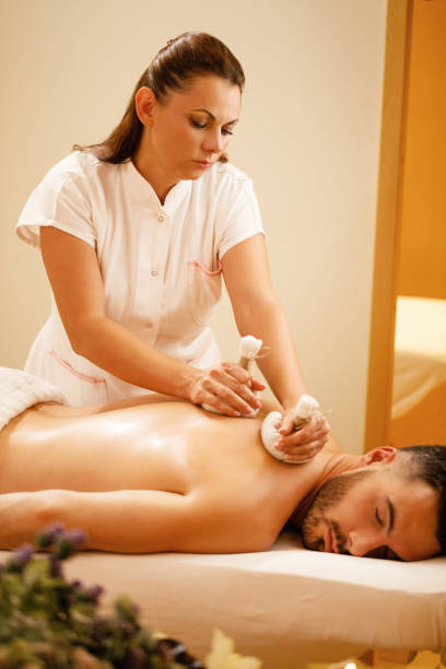 istock Female therapist using herbal balls while massaging man's back at the spa. 1182968427